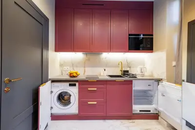 a kitchen with red cabinets and a washing machine at Apartamenty Limanowskiego in Kraków
