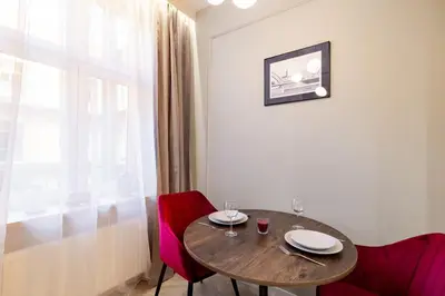 a dining room table with red chairs and a window at Apartamenty Limanowskiego in Kraków