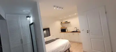 a white bedroom with a bed and a kitchen at ApartamentyM&K in Balice
