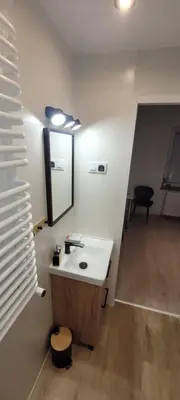 a bathroom with a sink and a mirror and a chair at ApartamentyM&K in Balice