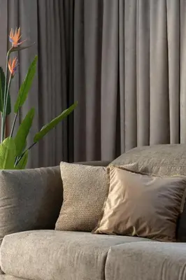 a couch with pillows in a living room with a plant at Klimatyzowany Apartament Blisko Parku w Krakowie z 3 Sypialniami, Wanną i Parkingiem by Renters Prestige in Kraków