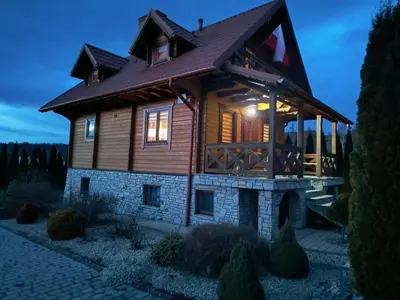 a log cabin with a porch and lights on at Domek Wypoczynkowy Relax in Bystra