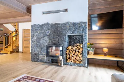 a fireplace in a living room with a pile of logs at Domek nad Potokiem 2 in Nowy Targ