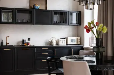 a kitchen with black cabinets and a table at Luksusowy Apartament na Podgórzu - by Upstairs in Kraków