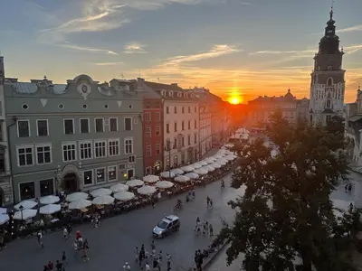 a city street at sunset with a clock tower at Queen's apartment from the 14th century - 130 m2 AC in Kraków