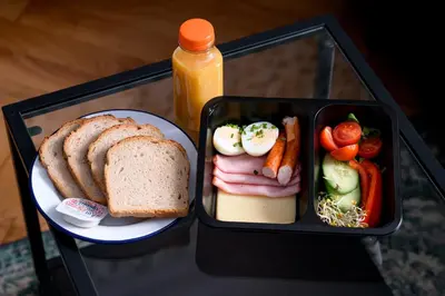 a lunch box with a sandwich and bread and vegetables at Native Apartments Lenartowicza 17 in Kraków