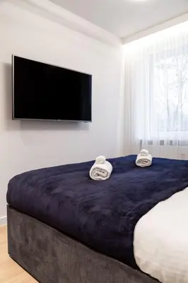 a bedroom with a large bed with a flat screen tv at Househost Apartment Retoryka in Kraków