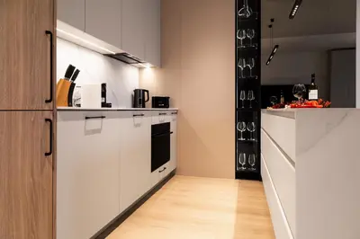 a kitchen with white cabinets and a wooden floor at Househost Apartment Retoryka in Kraków