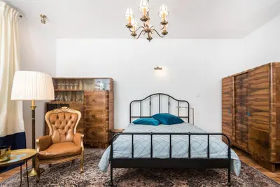 a bedroom with a bed and a chair and a chandelier at LION apartments - Elegance in Kraków