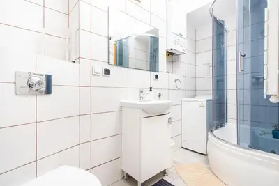 a white bathroom with a sink and a mirror at LION apartments - Elegance in Kraków