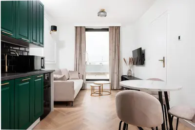 a kitchen with green cabinets and a living room at City of the Kings - Riverside K22 m44 in Kraków
