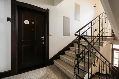 a hallway with a black door and stairs at Native Apartments Kraszewskiego 26 in Kraków