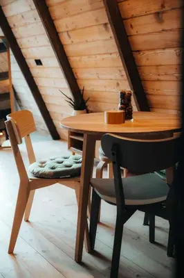 a wooden table with two chairs and a wooden ceiling at Budzi nas las Marcyporeba - Mały domek in Marcyporęba