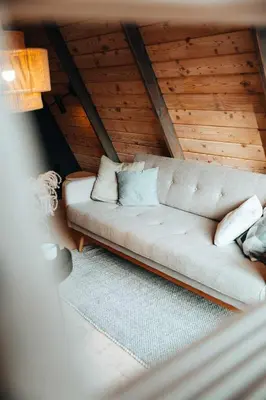 a living room with a couch in a attic at Budzi nas las Marcyporeba - Mały domek in Marcyporęba
