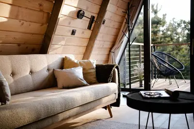 a room with a ladder and a couch and a table at Budzi nas las Marcyporeba - Mały domek in Marcyporęba