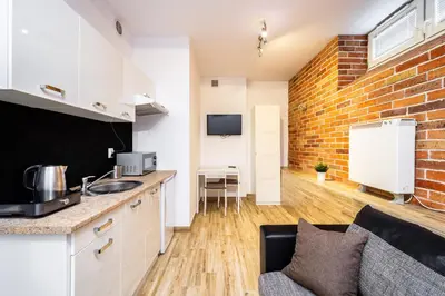a kitchen and living room with a brick wall at RentPlanet - Studio Mazowiecka in Kraków