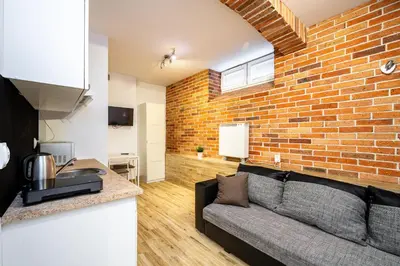 a living room with a couch and a brick wall at RentPlanet - Studio Mazowiecka in Kraków