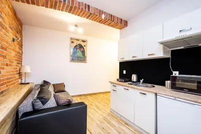 a living room with a couch and a kitchen at RentPlanet - Studio Mazowiecka in Kraków