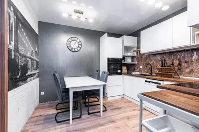 a kitchen with a table and chairs and a clock on the wall at Loft Apartment in Kraków