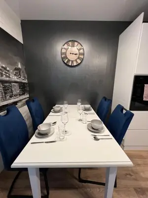 a white table with chairs and a clock on a wall at Loft Apartment in Kraków