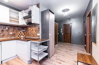 a kitchen with white cabinets and a wooden floor at Loft Apartment in Kraków