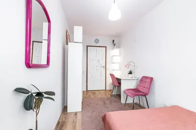 a bedroom with a pink bed and a table and chairs at Loft Apartment in Kraków