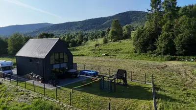 a small black shed in a field with a fence at Stodoła pod Bacówką Zawoja Sauna Jacuzzi in Skawica
