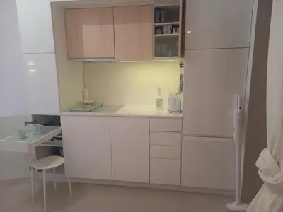 a small kitchen with white cabinets and a stool at Centrum Krakowa, apartament z ogrodem i parkingiem in Kraków