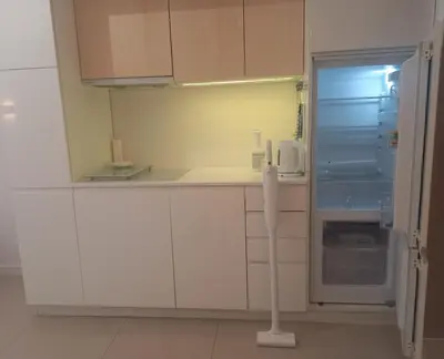 a white kitchen with a refrigerator and a microwave at Centrum Krakowa, apartament z ogrodem i parkingiem in Kraków