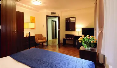 a hotel room with a bedroom with a bed and a chair at Armon Residence in Kraków