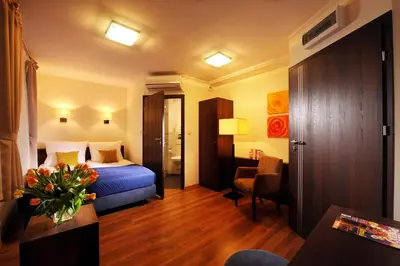 a hotel room with a bed and a desk and a chair at Armon Residence in Kraków