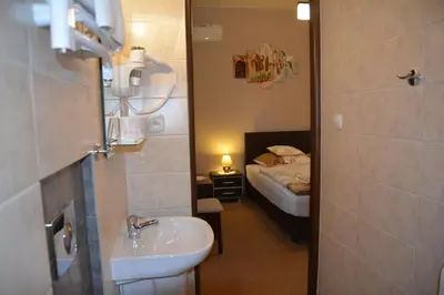 a bathroom with a sink and a bedroom with a bed at Astra Apartments in Oświęcim
