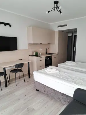 a room with two beds and a desk and a kitchen at Sympo Apartments in Kraków