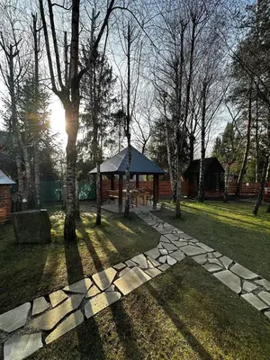 a stone path in a park with a gazebo at Sękata Chata - drewniany domek z jacuzzi in Osieczany