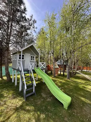 a playground with a slide and a house at Sękata Chata - drewniany domek z jacuzzi in Osieczany