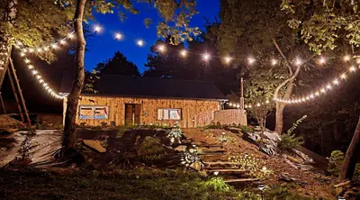 a log cabin with lights in a yard at night at Chałupa na Wierzchowinie in Limanowa