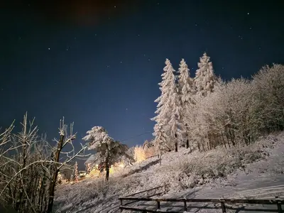 a snow covered hill with trees at night at CzarnyHetman in Grzechynia