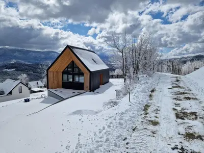 a small wooden cabin in the snow with a snowy road at CzarnyHetman in Grzechynia