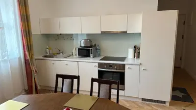 a small kitchen with white cabinets and a table at Two Bedrooms City Center Krakow in Kraków