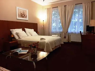 a bedroom with a bed and a table and windows at Red Carpet Hostel in Kraków