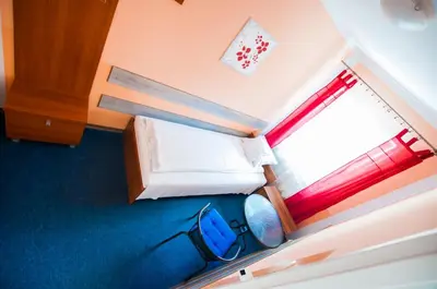 a small bedroom with a bed and a window at Red Carpet Hostel in Kraków