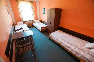 a room with two beds and a desk and a window at Red Carpet Hostel in Kraków