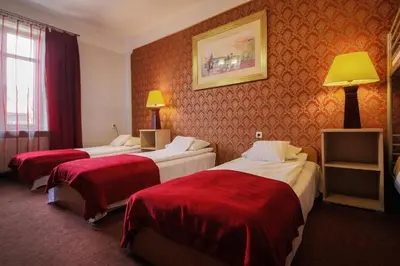 a hotel room with three beds with red sheets at Red Carpet Hostel in Kraków
