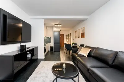 a living room with a black leather couch and a table at Apartments Deluxe Barcelona 55 by BookingHost in Kraków