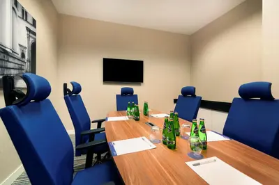 a conference room with a long wooden table and blue chairs at Hampton by Hilton Krakow in Kraków