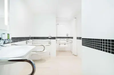 a white bathroom with a sink and a shower at Hampton by Hilton Krakow in Kraków