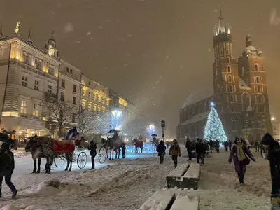 a group of people walking in a snow covered city at night at Yesblisko in Kraków