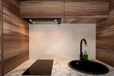 a bathroom with a black sink and wooden walls at Main Station Stay in Kraków