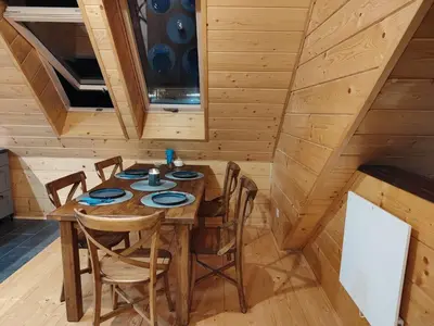 a dining room with a wooden table and chairs at Dzika Dziura z jacuzzi in Zawoja