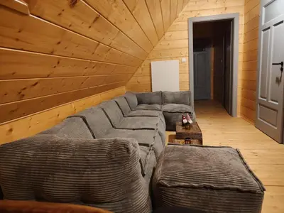 a living room with a gray couch and wooden walls at Dzika Dziura z jacuzzi in Zawoja